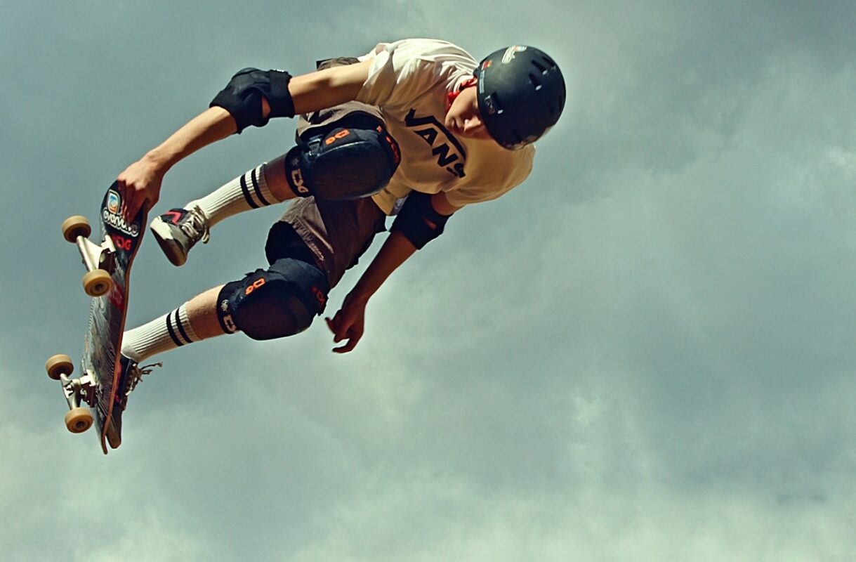 A child putting on a skate helmet and knee pads